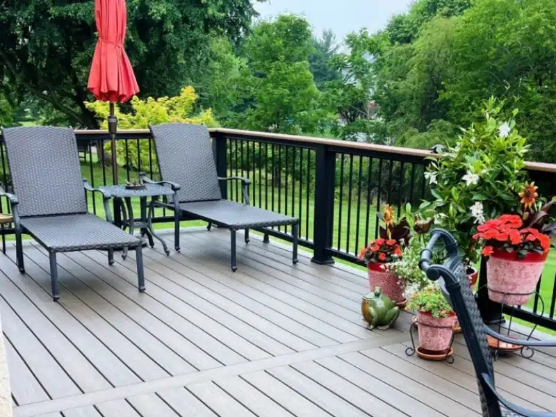 raised-deck-with-outdoor-chairs-and-table-with-red-closed-umbrella-featuring-beautiful-colorful-potted-plants-and-trees-on-the-background-in-south-east-pa