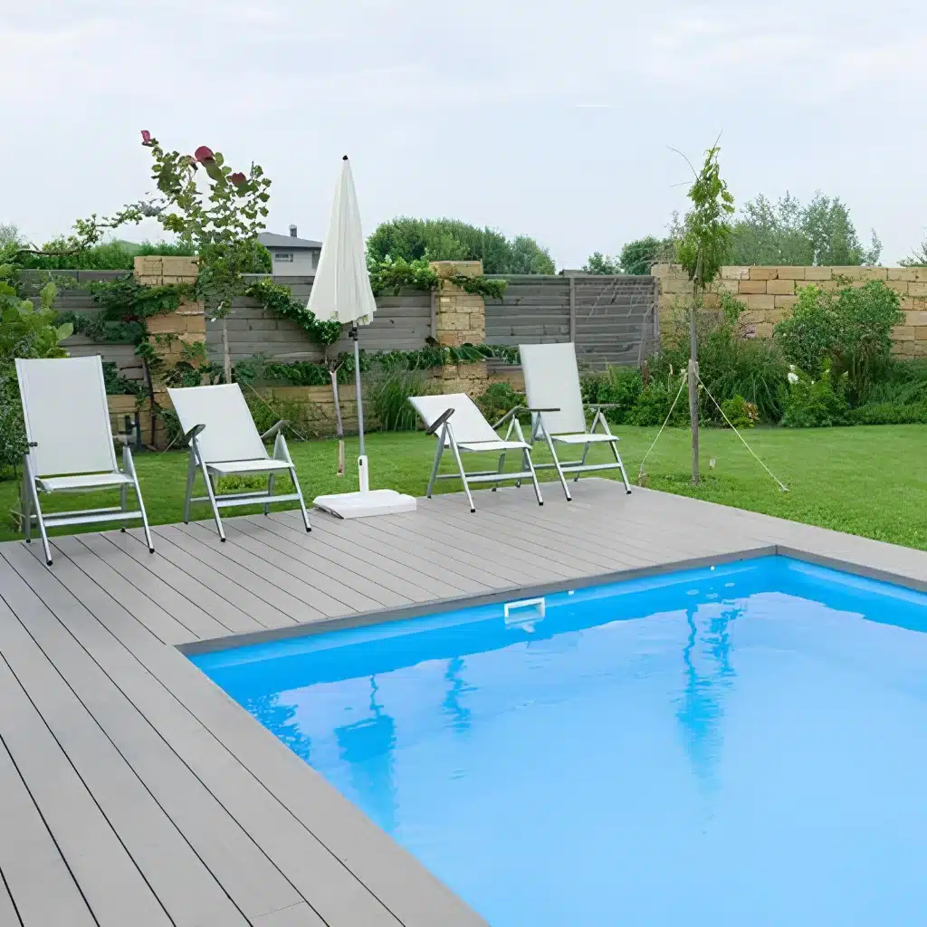 residential-deck-with-a-pool-and-lounge-featuring-brick-wall-privacy-fence-surrounded-by-grass-and-plants-in-south-east-pa